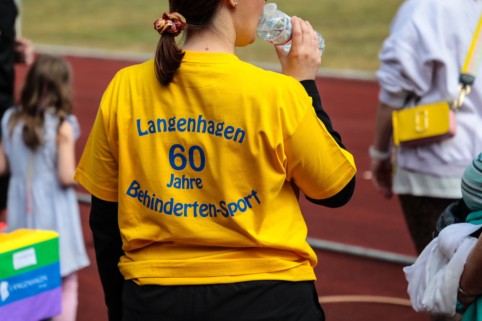 Frau von hinten mit gelbem T-Shirt mit der Aufschrift 60 Jahre Behindertensport Langenhagen